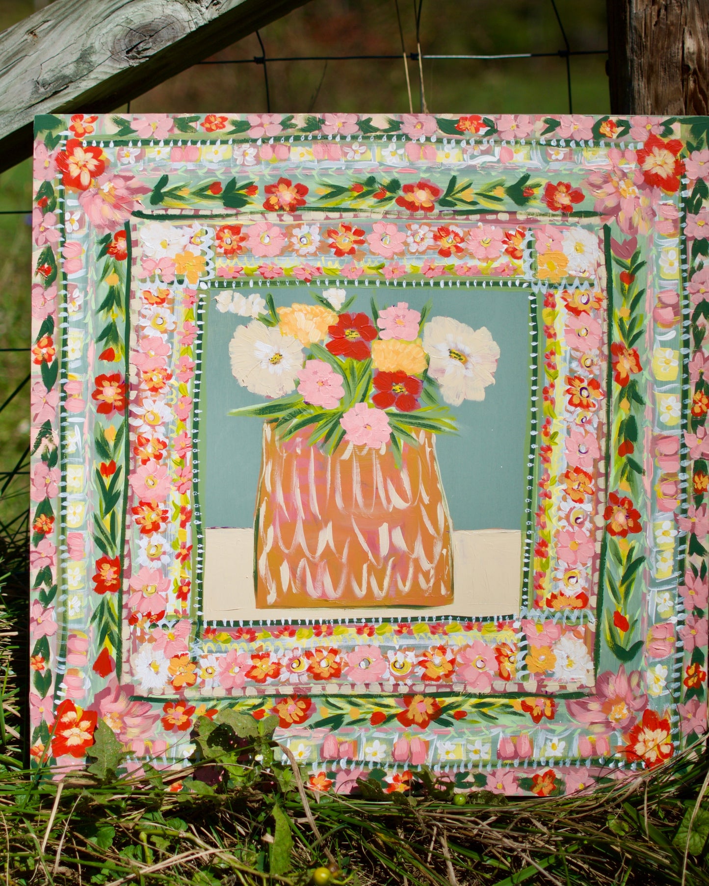 Floral quilt with a vase of flowers in the center, set against a natural background.