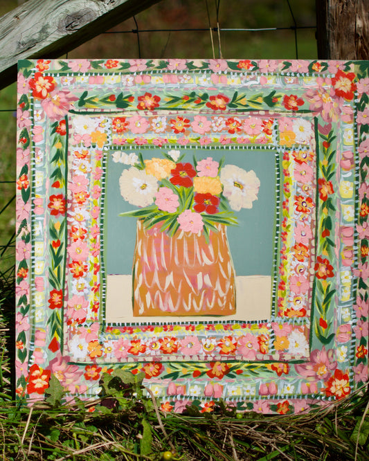 Floral quilt with a vase of flowers in the center, set against a natural background.